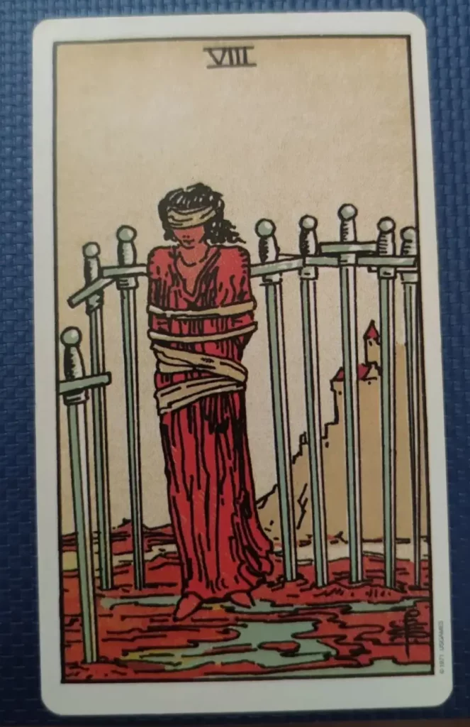 tarot Rider-Waite huit d’épées femme ligotée entourée d’épées symbolisant l’enfermement mental